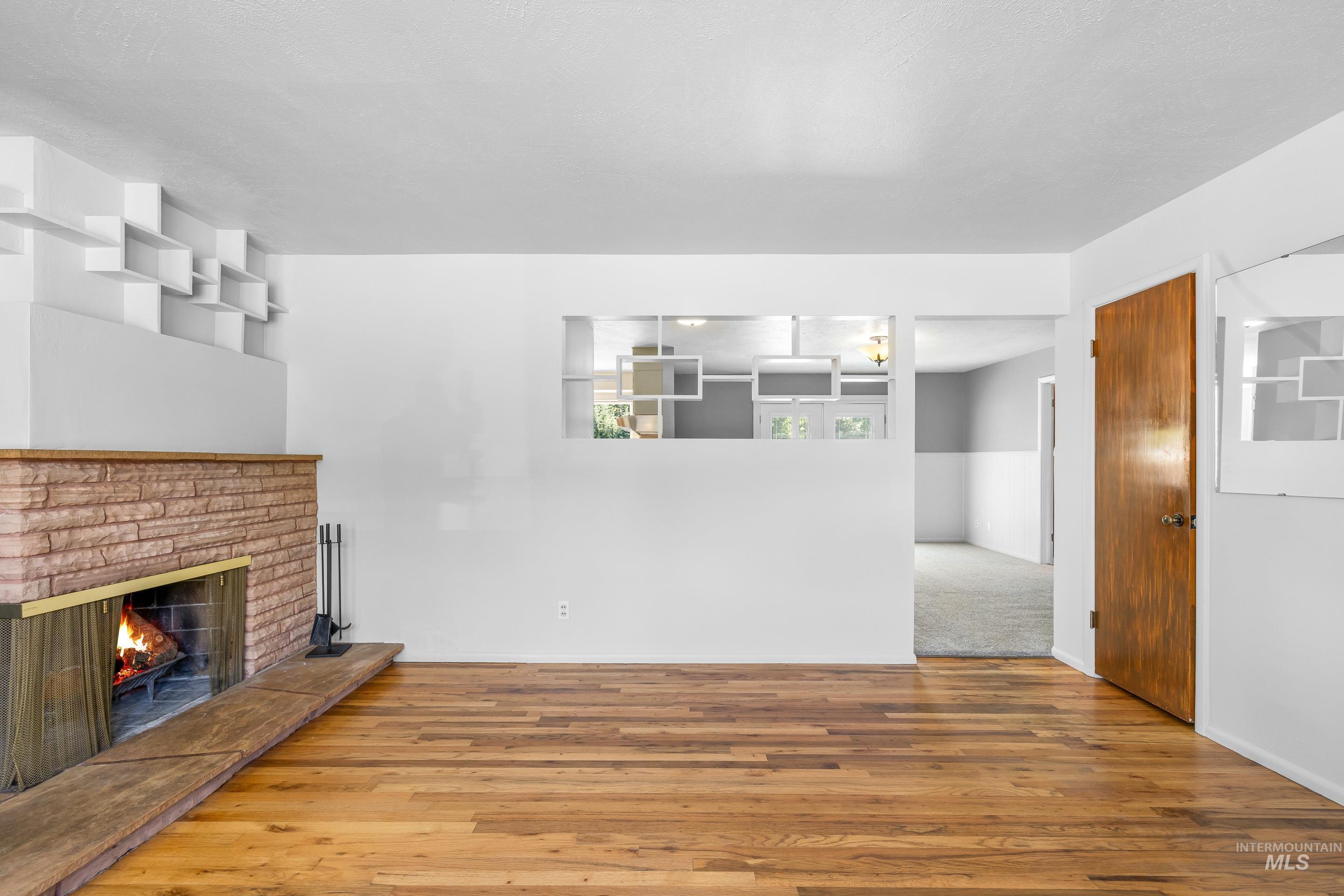 708 South Phillippi Street Boise, ID 83705 - Photo 3 of 25 Living area featuring wood-finish flooring, a brick-surround fireplace with a wood hearth, and built-in wall shelving