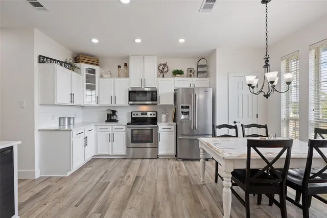 a kitchen with white cabinets stainless steel appliances and dining table