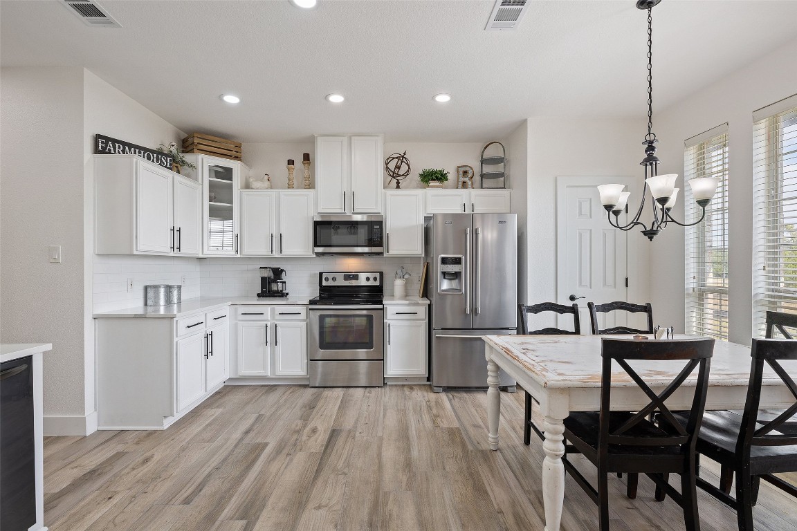 213 Beauchamp Road Dripping Springs, TX 78620 - Photo 11 of 40 a kitchen with white cabinets stainless steel appliances and dining table