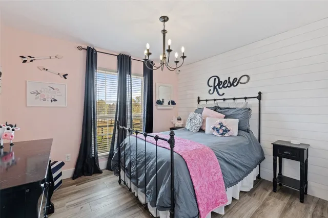 a bedroom with a bed chandelier and a window