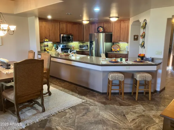 a kitchen with stainless steel appliances granite countertop table chairs sink and cabinets
