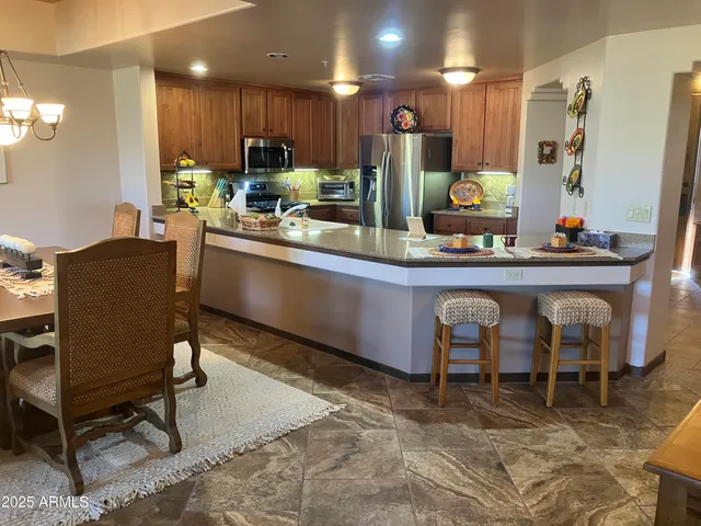 a kitchen with stainless steel appliances granite countertop table chairs sink and cabinets