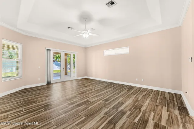 an empty room with wooden floor and windows