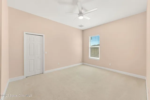 an empty room with a ceiling fan and a window