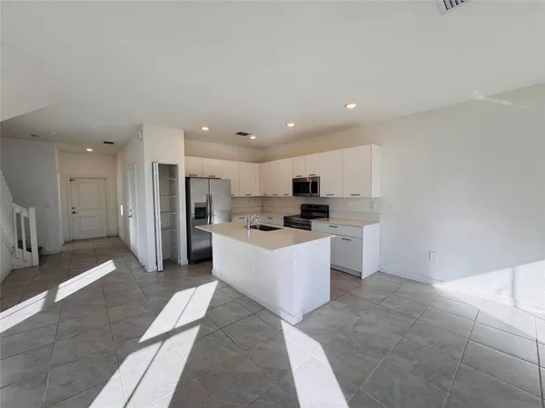a large kitchen with kitchen island a sink a counter top space and stainless steel appliances
