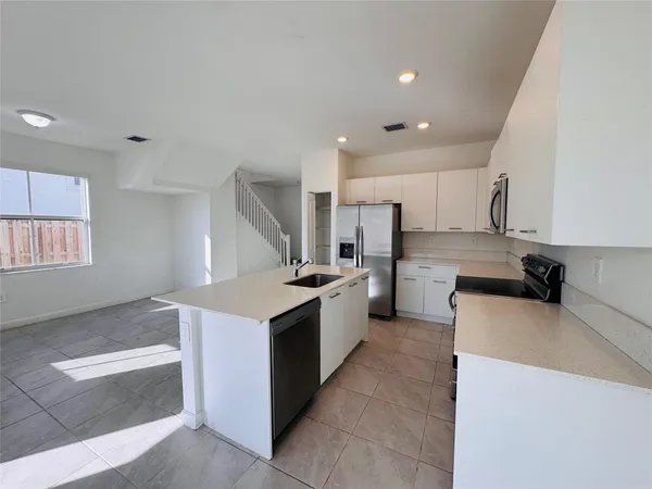 a large kitchen with stainless steel appliances kitchen island granite countertop a sink and a stove