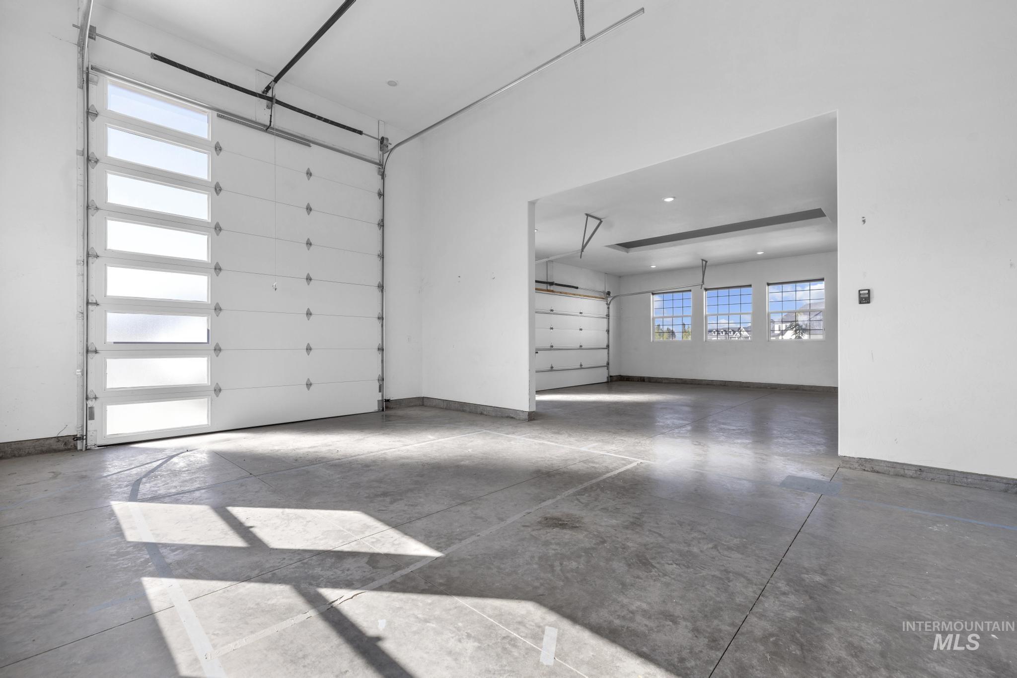 4280 Rim Vista Road Filer, ID 83328 - Photo 44 of 50 Spacious garage featuring a modern sectional overhead door with frosted glass panels, durable concrete flooring, and multiple windows providing natural illumination