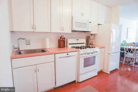a kitchen with white cabinets and white appliances