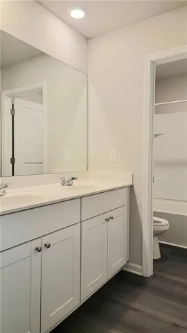 a bathroom with a granite countertop sink toilet and a mirror