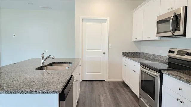 a kitchen with granite countertop cabinets stainless steel appliances and wooden floor