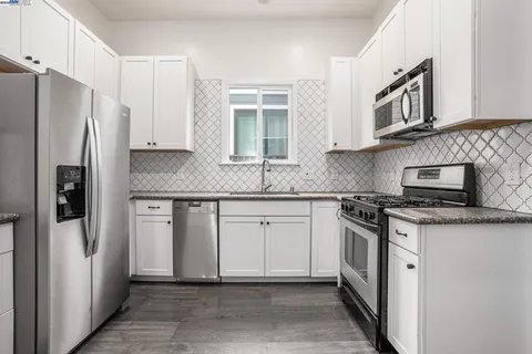 a kitchen with stainless steel appliances granite countertop a refrigerator sink and stove