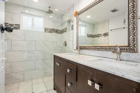 a bathroom with a granite countertop sink a mirror and a shower