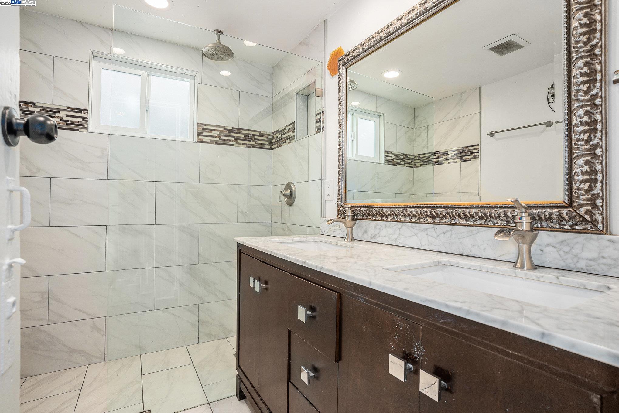 185 7th Street Oakland, CA 94607 - Photo 19 of 20 a bathroom with a granite countertop sink a mirror and a shower