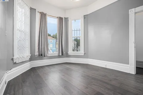 an empty room with wooden floor and windows with curtains view