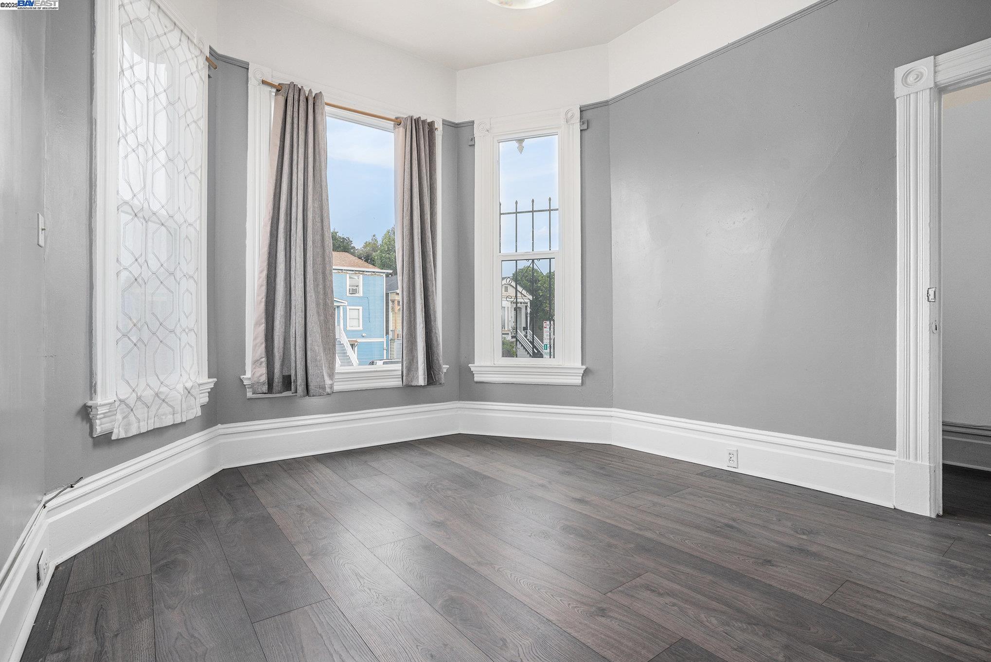 185 7th Street Oakland, CA 94607 - Photo 6 of 20 an empty room with wooden floor and windows with curtains view