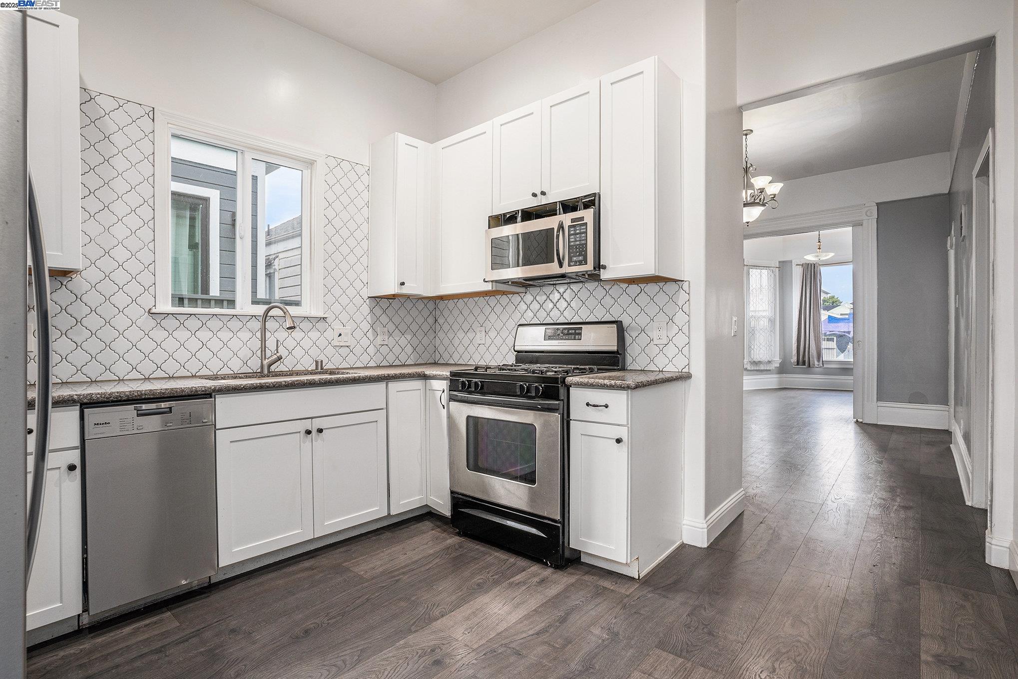 185 7th Street Oakland, CA 94607 - Photo 10 of 20 a kitchen with stainless steel appliances granite countertop a stove top oven a sink dishwasher and a refrigerator with wooden floor