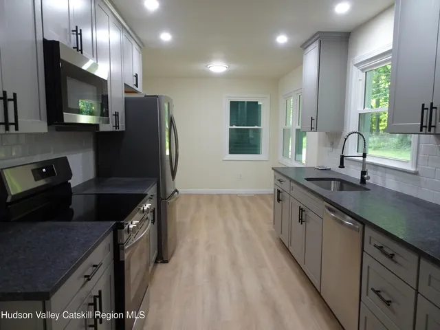 a kitchen with stainless steel appliances granite countertop a sink a stove and a refrigerator