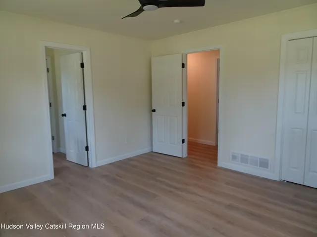 a view of an empty room with wooden floor and closet