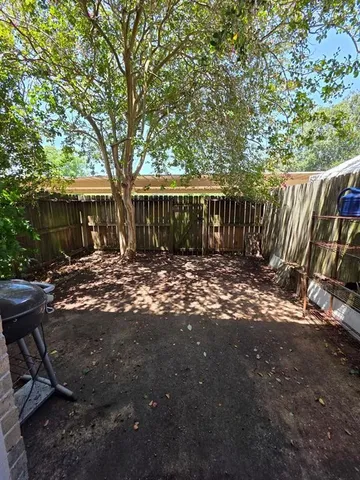 a view of backyard with tree and wooden fence