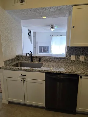 a kitchen with granite countertop a sink cabinets and wooden floor