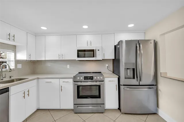 a kitchen with white cabinets and stainless steel appliances
