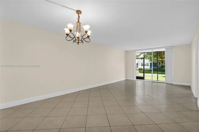 a view of an empty room with chandelier fan and fire place