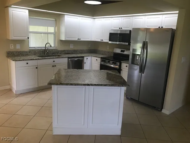 a kitchen with stainless steel appliances granite countertop a sink and a refrigerator