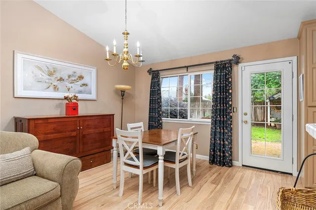 a dining room with wooden floor a chandelier a wooden table and chairs