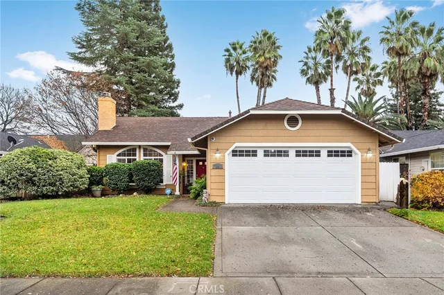 a view of a white house with a yard plants and palm trees
