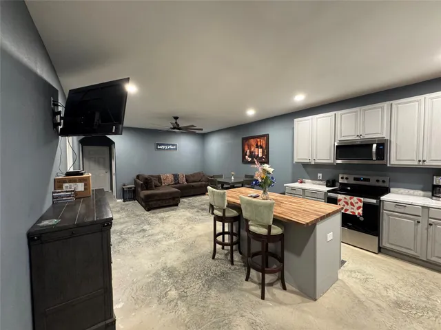 a living room with furniture a flat screen tv and kitchen view