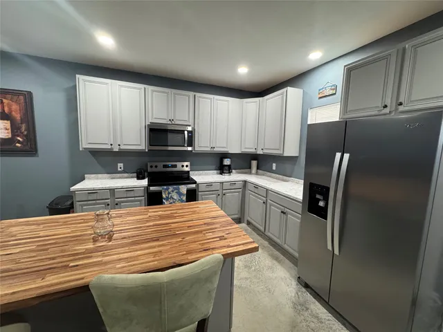 a kitchen with granite countertop a refrigerator stove top oven and sink