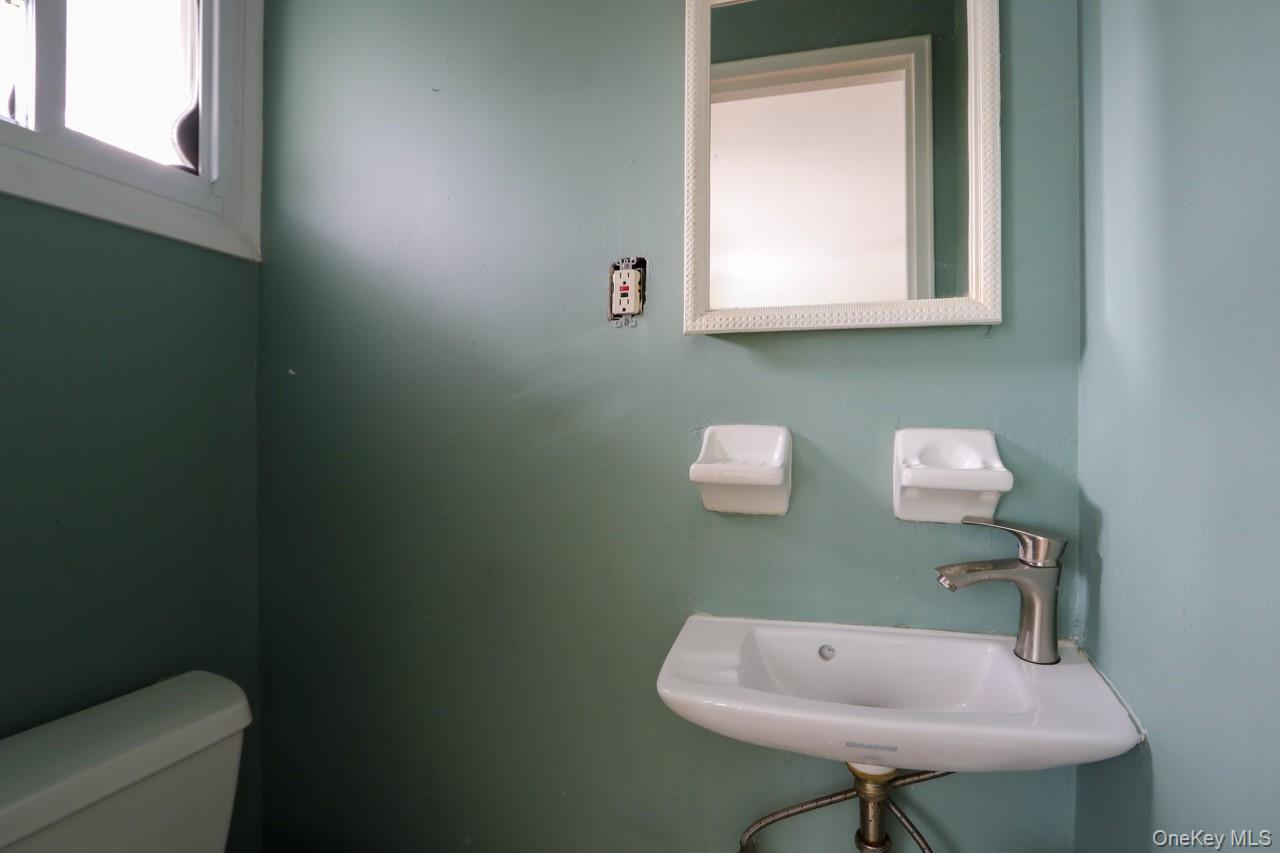 12-67 Waterview Street Queens, NY 11691 - Photo 7 of 14 a bathroom with a toilet a sink and a mirror