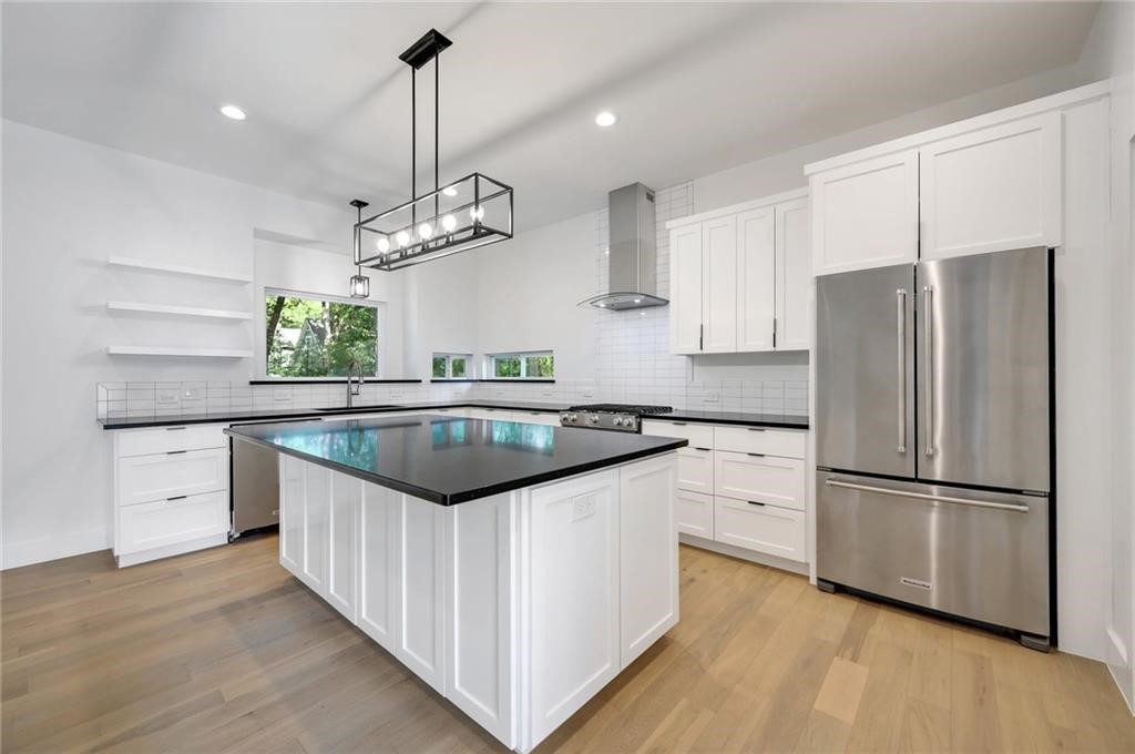 a kitchen with granite countertop stainless steel appliances a refrigerator a sink and a cabinets