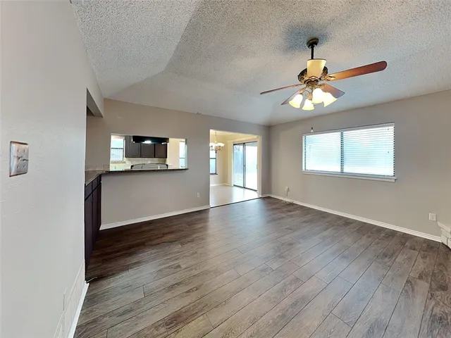 an empty room with wooden floor fan and windows
