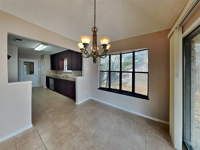 a view of a livingroom with a fireplace a window and a chandelier