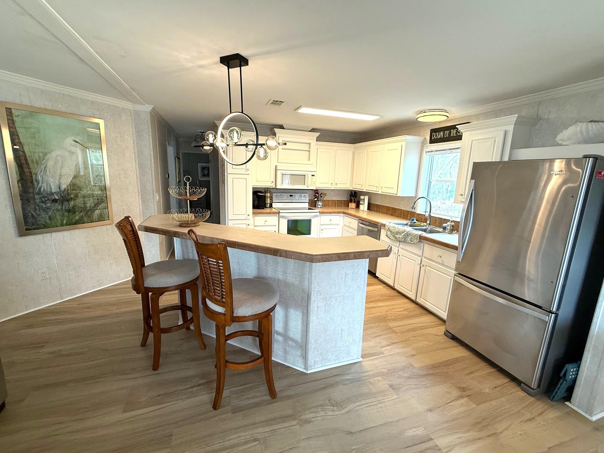 292 Majorca Road St. Augustine, FL 32080 - Photo 6 of 32 Kitchen with stainless steel appliances, crown molding, a breakfast bar, hanging lights, and light wood-type flooring