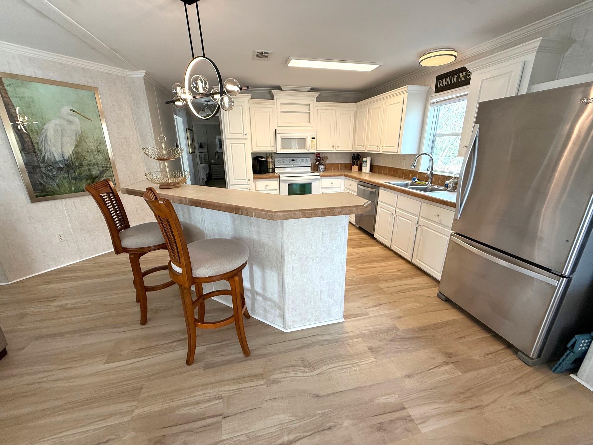 292 Majorca Road St. Augustine, FL 32080 - Photo 10 of 32 Kitchen with stainless steel appliances, a kitchen bar, light wood-type flooring, crown molding, and white cabinetry