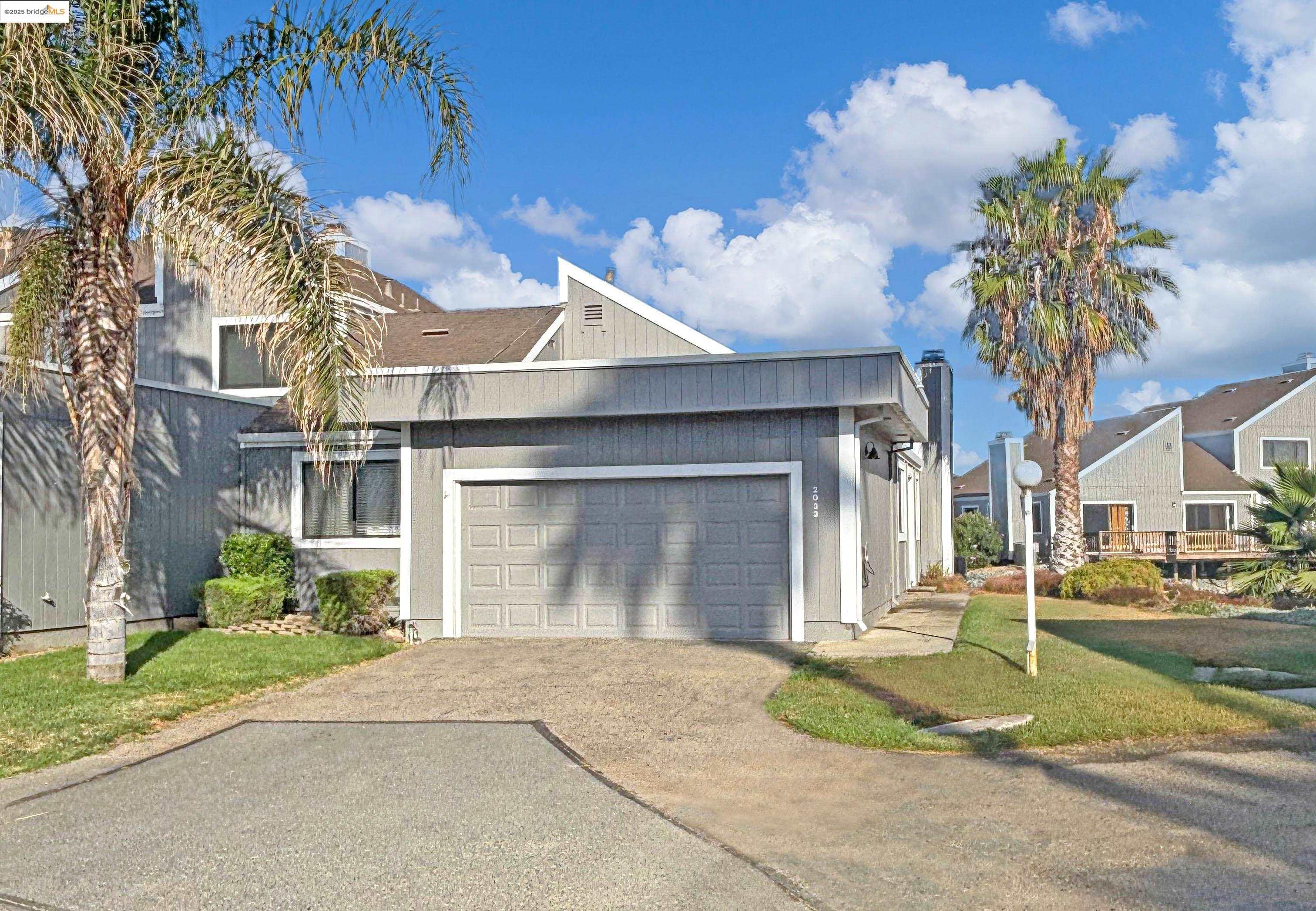View of front of house featuring driveway, an attached garage, a chimney, and a front lawn