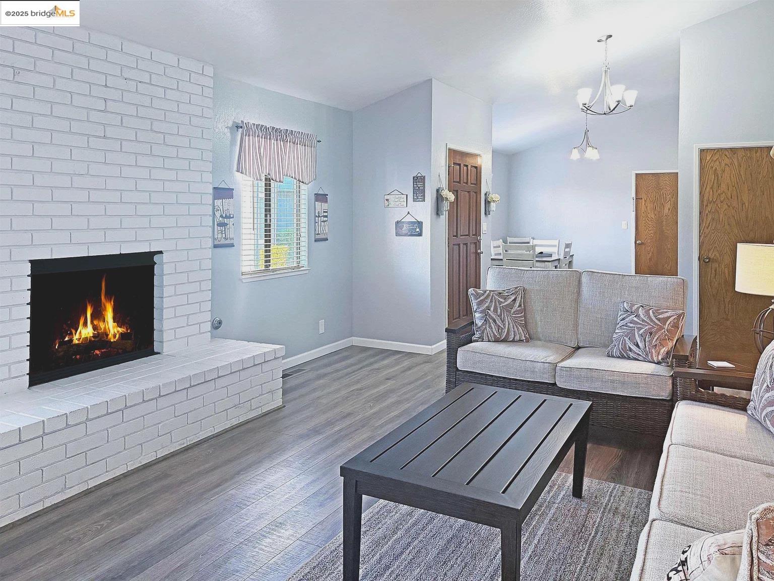 2033 Sand Point Road Discovery Bay, CA 94505 - Photo 5 of 17 Living area with wood finished floors, a fireplace, and a chandelier