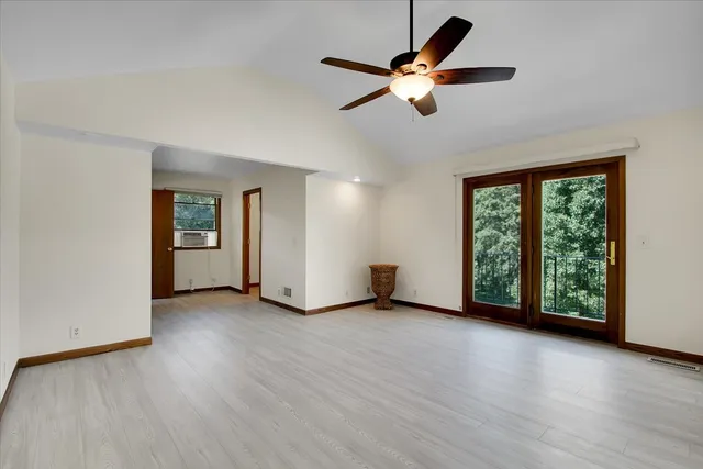 an empty room with wooden floor fan and windows