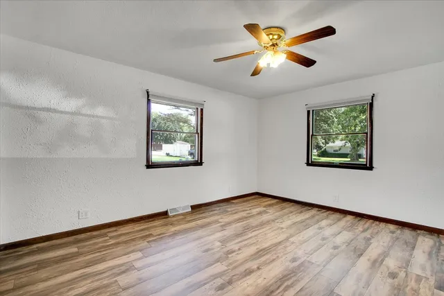 a view of an empty room with window and wooden floor