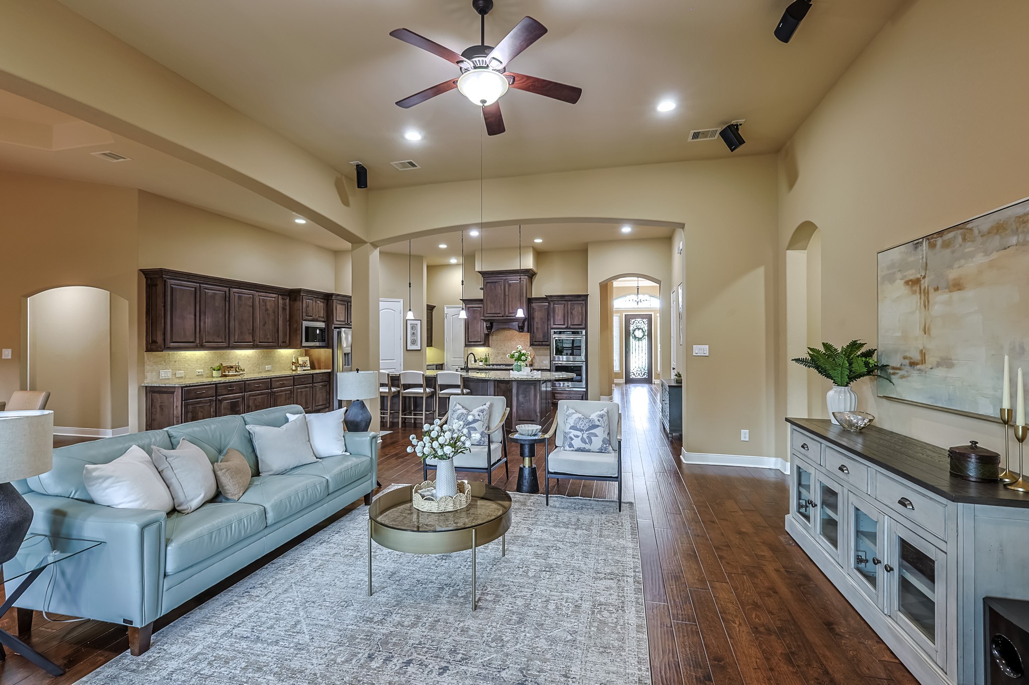 515 Mill Creek Road Pinehurst, TX 77362 - Photo 8 of 48 Spacious open-concept living area with high ceilings and warm wood flooring. The room features a cozy seating arrangement and a modern kitchen with dark cabinetry and stainless steel appliances. Natural light enhances the inviting atmosphere.