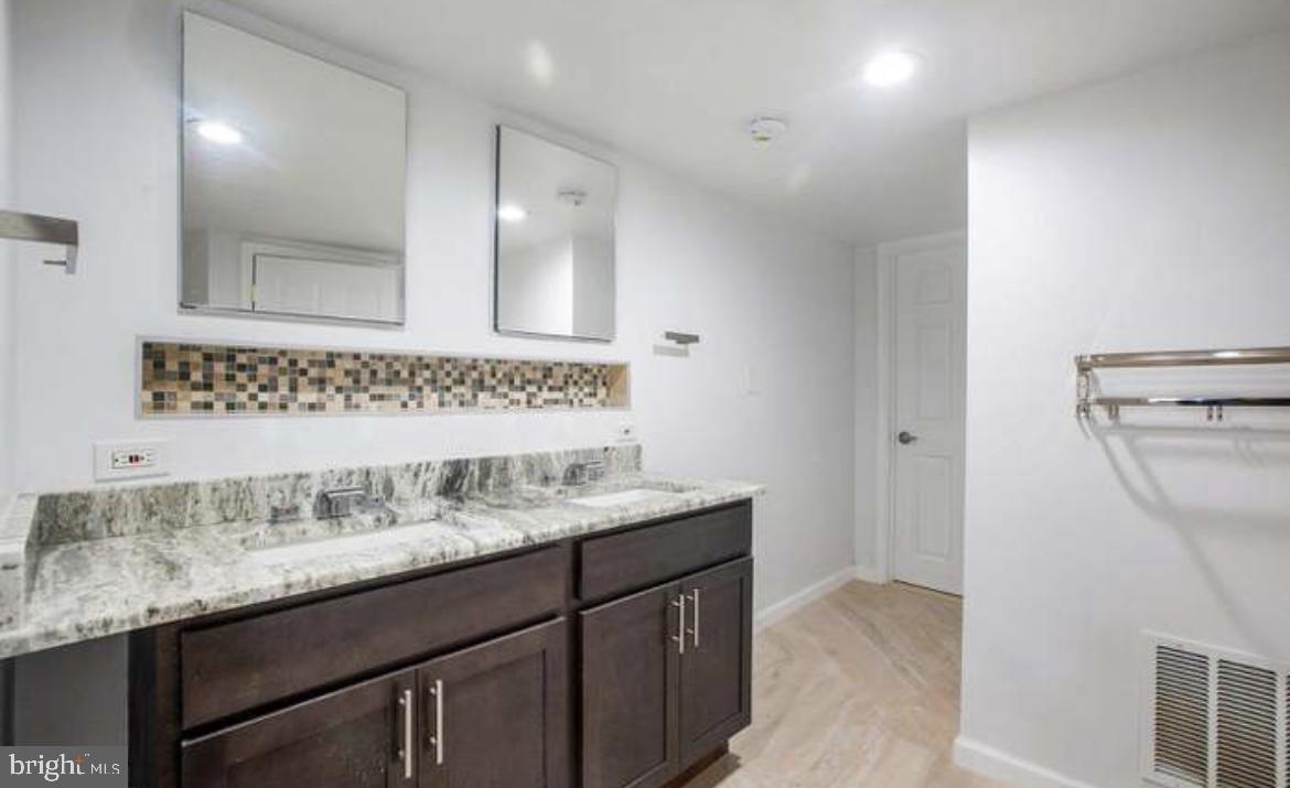 815 North Calhoun Street Baltimore, MD 21217 - Photo 37 of 38 a bathroom with a granite countertop sink a mirror and a shower