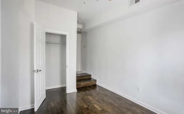 a view of a room with wooden floor and a white wall