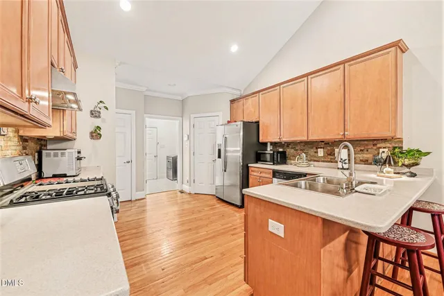 a kitchen with stainless steel appliances granite countertop a stove a sink dishwasher and a refrigerator with wooden floor