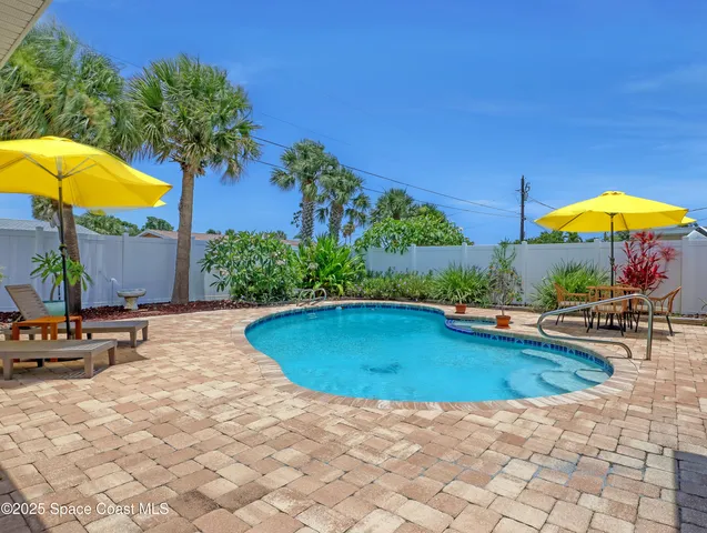 a view of pool with lawn chairs under an umbrella
