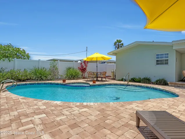 a view of a swimming pool with a table and chairs under an umbrella