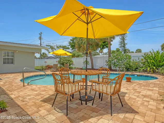 a patio with a table and chairs under an umbrella