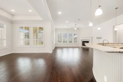 an empty room with wooden floor and a kitchen