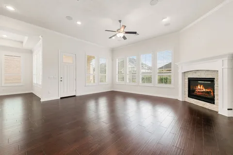 an empty room with wooden floor fireplace and windows